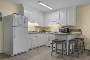 a kitchen with white cabinets and a white refrigerator at Boardwalk Shores A Duplex in Atlantic Beach