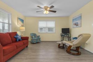 a living room with a red couch and a ceiling fan at Boardwalk Shores A Duplex in Atlantic Beach