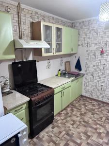 Una cocina con gabinetes verdes y una estufa. horno superior en House, en Aktobe 1 foto más