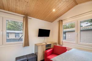 a room with a bed and a tv and a red chair at Mobilheim Für 2 Personen 2 Kinder Ca 36 M Sup2 In Lohmen, Mecklenburgische Seenplatte in Lohmen