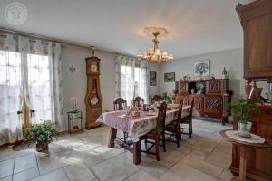 a dining room with a table and chairs and a clock at Au plein soleil in Chazelles-sur-Lyon