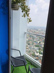 a balcony with two chairs and a view of a city at Apartemen puri mansion in Jakarta