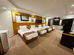 a hotel room with three beds and a television at فندق المغاربي للشقق الفندقية in Al Madinah