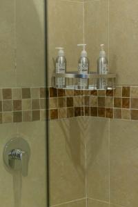 three bottles ofodorizers sit on a shelf in a shower at Trisan Resident Hotel in Nairobi
