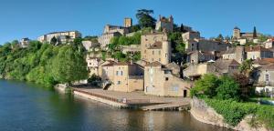 a group of buildings on a hill next to a river at LES REFUGES DU LOT Kouki's Lodge in Mauroux