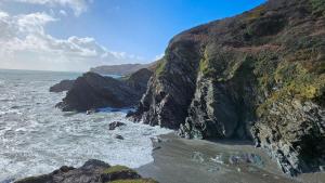 a rocky shoreline with the ocean and a beach at Talland Cottage 4 bedroom with Hot Tub in Looe