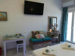 a living room with a table and a tv on the wall at Fantastic View Suite Kythnos in Kithnos