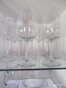 un montón de copas de vino sentadas en una estantería de cristal en Cypres, modern wooden house with free parking, en Gračec
