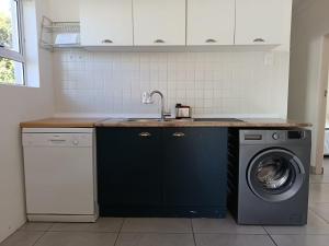 a kitchen with a sink and a washing machine at Hartsepunt in Mossel Bay
