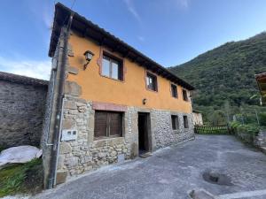 a stone building with a driveway next to a mountain at El Refugio de Júlia in Mier