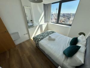 a bedroom with a bed with pillows and a window at Two Bedroom City View Apartment Liverpool in Liverpool