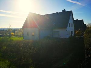 a white house with the sun shining on it at Das Burgberghaus Apartment Auwald in Hürtgenwald
