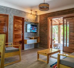 a living room with a tv on a brick wall at Village Choça in Acaraú