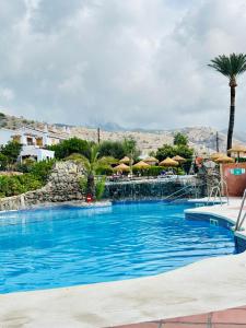 Una gran piscina con agua azul y sombrillas. en Right by the pool area in Capistrano Village!, en Nerja