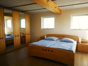 a bedroom with a large wooden bed with blue pillows at Das Burgberghaus Apartment Auwald in Hürtgenwald