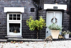 a black brick house with a white door and two potted plants at 'The Den' - Malvern - A King Size or Twin Beds plus a Sofa Bed in Great Malvern