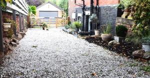 a gravel driveway with potted plants on the side of a house at 'The Den' - Malvern - A King Size or Twin Beds plus a Sofa Bed in Great Malvern