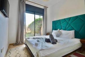 马拉喀什Oasis de l'Atlas by Golf Resort的一间卧室配有一张带绿色床头板的床和窗户 更多36张照片