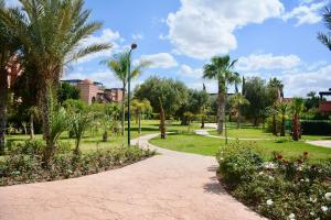 马拉喀什Oasis de l'Atlas by Golf Resort的棕榈树公园和人行道