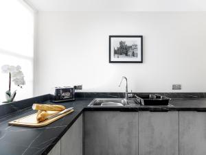 a kitchen counter with a sink and a cutting board with bread at Castle Street Apartments - Luxury Scalpsie Apartment in Rothesay