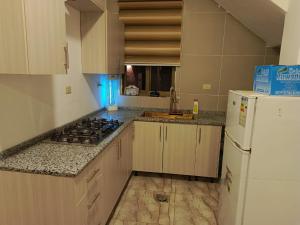 a kitchen with a stove and a white refrigerator at شاليه الاميرات in Sowayma