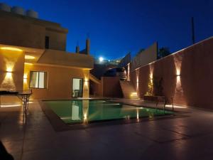 a house with a swimming pool at night at شاليه الاميرات in Sowayma