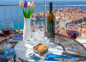 einen Tisch mit einer Flasche Wein und einer Vase Blumen in der Unterkunft Apartment Superb View 2 in Dubrovnik