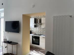 a kitchen with white cabinets and a tv on the wall at Riviera Suite Via Eveneto, 47 in Syracuse