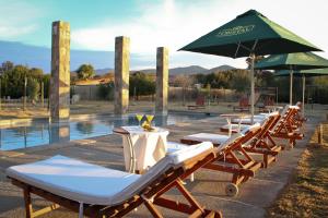 a row of lounge chairs with an umbrella and a pool at Hotel Limari in Ovalle