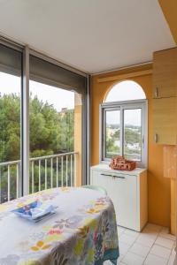 Schlafzimmer mit einem Bett und einem Balkon mit Fenstern in der Unterkunft Le Nautilus in Gruissan