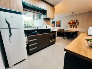 a kitchen with a white refrigerator and a table at Casa Nanda Lima em Pomerode 2 quartos in Pomerode