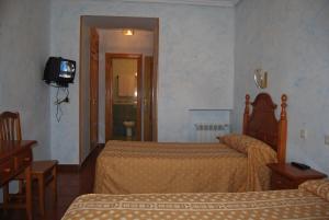 una camera d'albergo con due letti e una televisione di Hostal Bellas ad Ávila