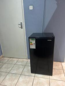 a black refrigerator sitting in a room next to a door at Rest Assured in Roodepoort +5 photos