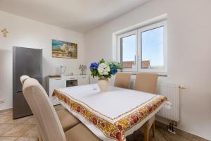 a dining room with a table with a vase of flowers on it at Apartments Barjaktarić in Malinska