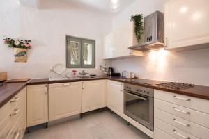 a kitchen with white cabinets and a stove top oven at Sun Drop 1 with private pool, 5-min walk to Drios beach in Drios