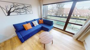 a living room with a blue couch and a large window at Charme du Mont d'Or in Métabief