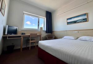 a hotel room with a bed and a desk with a computer at Green Park Hotel Klaipeda in Klaipėda