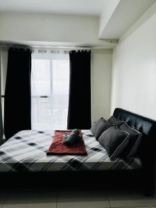 a bedroom with a bed and a window with black curtains at Wind Suites Tagaytay Condotel in Tagaytay