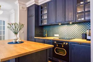 eine Küche mit blauen Schränken und einer hölzernen Arbeitsplatte in der Unterkunft Le Petit Okopowa - apartament w centrum Lublina in Lublin + 5 Fotos