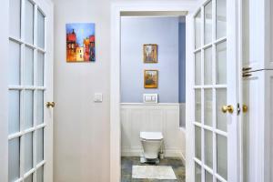 ein Badezimmer mit Toilette und Gemälden an der Wand in der Unterkunft Le Petit Okopowa - apartament w centrum Lublina in Lublin