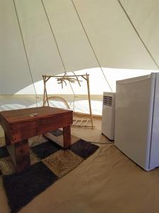 a wooden table and a refrigerator in a tent at Camping B&B La Contea in SantʼAnna Arresi +19 photos