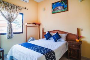 a bedroom with a bed with blue pillows and a window at Capital O Hotel Aurora, Tuxtla Gutiérrez in Tuxtla Gutiérrez