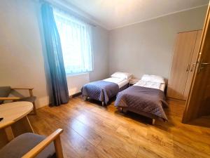 a room with two beds and a table and a window at Willa Maczek in Sztutowo +2 photos