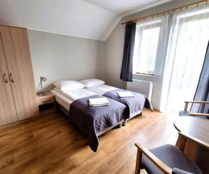 a bedroom with two beds and a table and window at Willa Maczek in Sztutowo