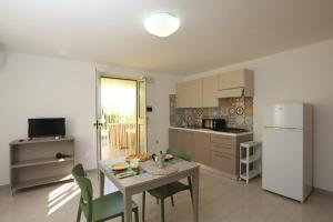 een keuken met een tafel, stoelen en een koelkast bij Villa Hibiscus in Vieste