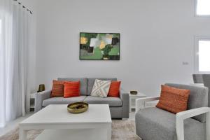 a living room with two chairs and a couch at Aphrodite Gardens Stunning Villa by VICHY Holidays in Paphos