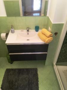 un lavabo de salle de bain avec deux serviettes jaunes dessus dans l'établissement Alloggio Turistico via dei Faggi - Room, à Rome