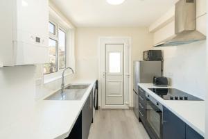 una cucina bianca con lavello e frigorifero di 2 bed, FREE parking, SKY a Bedford Altre 10 foto