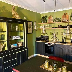 a kitchen with green walls and a counter with a microwave at Highclass-Urlaub in Ostfriesland in Westoverledingen +1 photo