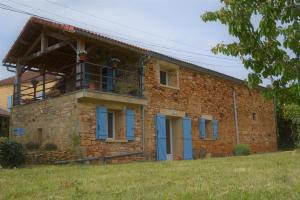 een bakstenen huis met blauwe ramen en een balkon bij Gîte de la brasserie in Prayssac +7 foto's